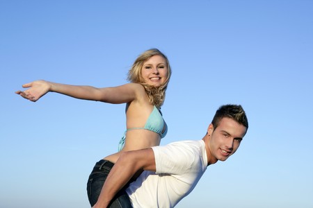 Young beautiful couple playing ourtdoor over blue skyの写真素材