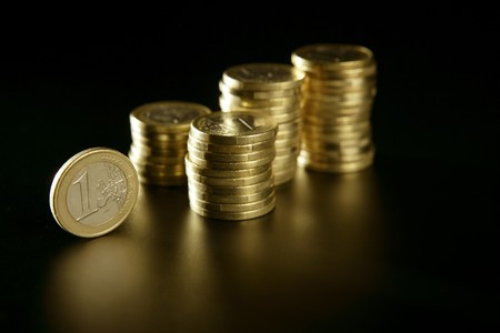 Euro currency coin columns with golden reflections over black