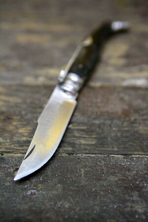 Open knife hand weapon over an aged wooden tableの写真素材