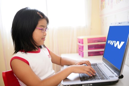 Asian little girl playing on internet with laptop computer, www sign