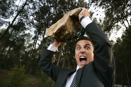 Angry businessman in outdoor forest, big stone in handsの写真素材
