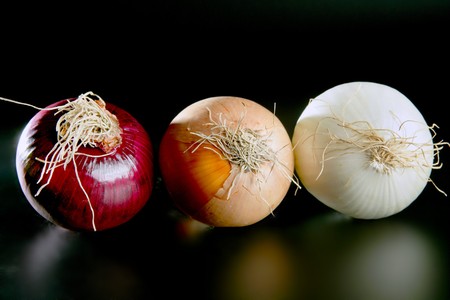 Three onion colors in a row isolated over black backgroundの写真素材