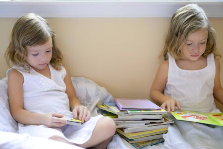 Beautiful twin little girls doing school homework at homeの写真素材