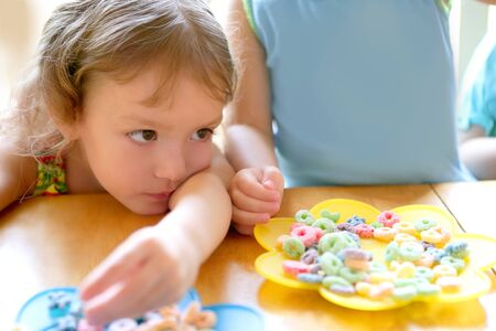 Two little sister girls eating together on the tableの写真素材