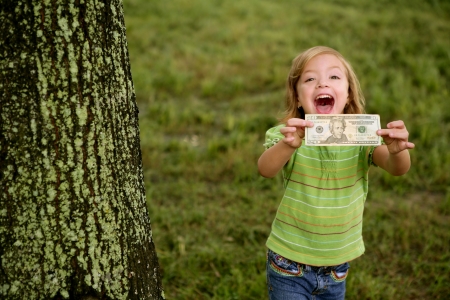 Beautifull happy little girl with dollar noteon her hands