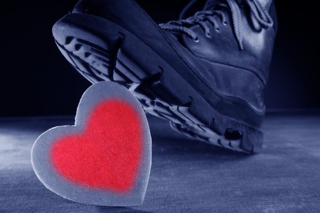 Kill the love or health metaphor. Boot treading a red valentines heartの写真素材