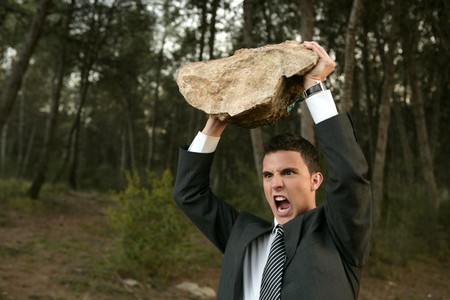 Angry businessman in outdoor forest, big stone in handsの写真素材