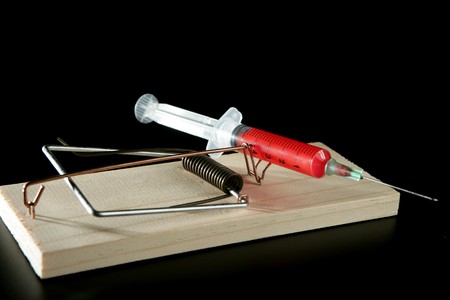 Drugs and medicine addiction metaphor. Color syringe on mouse trapの写真素材