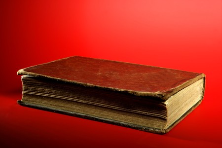 Old aged classic book close up over red backgroundの写真素材