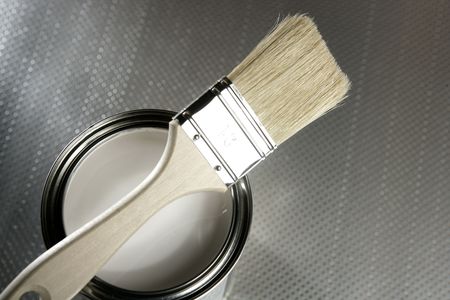 Painter brush and white paint tin macro over silver pattern background