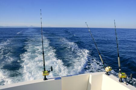 Fishing boat with three big game rods an reels, ocean blue seaの写真素材