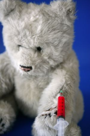 Teddy bear on the doctor, with bloody vaccine syringe on its arm  の写真素材