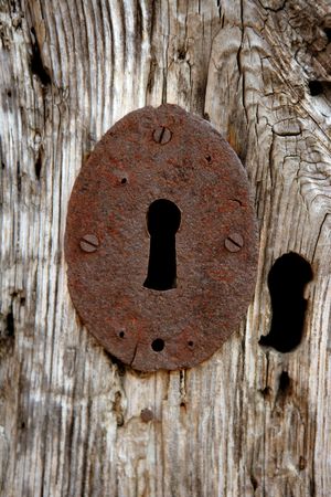 Key hole over aged gray old wood, rusty metalの写真素材