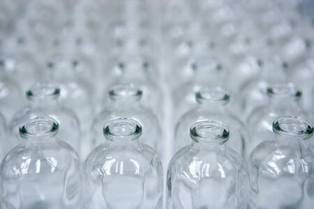 Glass transparent empty bottles in rows, cosmetics assembly line