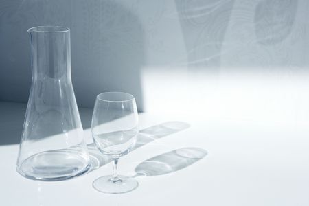 Water glass and bottle with transparent shadows in white kitchenの写真素材