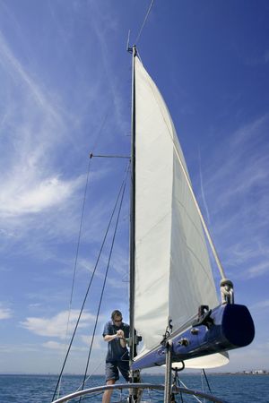 Sailor in sailboat rigging the sails over sunny summer blue skyの写真素材