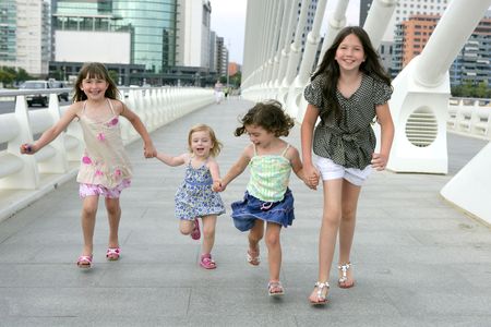 Four little girl group walking in the city bridge downtown buildingsの写真素材