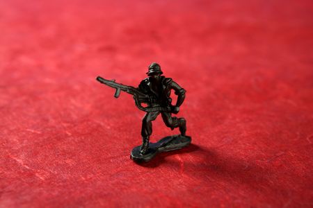 Plastic toy soldier over red background, war metaphorの写真素材