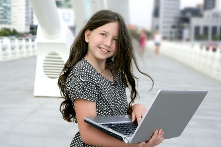 Beautiful little girl with laptop computer downtown city bridgeの写真素材