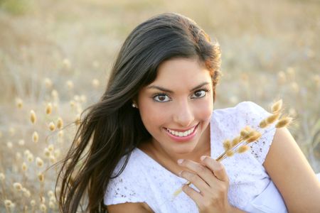 Beautiful indian brunette having a rest on a golden summer fieldの写真素材