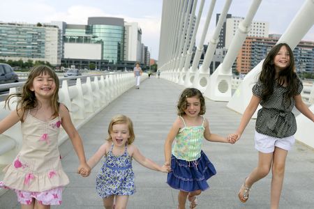 Four little girl group walking in the city bridge downtown buildingsの写真素材