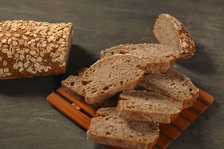 Cereal bread loaf slices over dark wood backgroundの写真素材