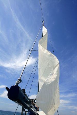 Sailor in sailboat rigging the sails over sunny summer blue skyの写真素材