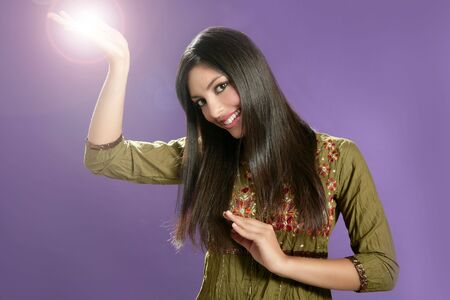 Beautiful indian young brunette woman posing hands on purple backgroundの写真素材