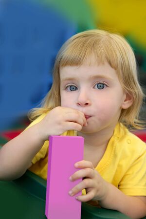 Beautiful blond girl drinking pink juice with strawの写真素材