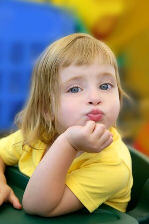 Blond little girl funny expression in her mouth in colorful backgroundの写真素材