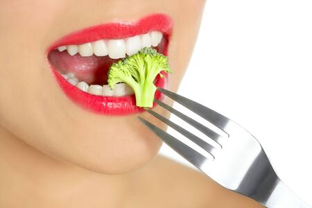 Broccoli on steel fork in woman mouth with red lipsの写真素材