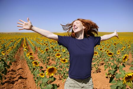 Happy redhead woman in sunflowers field outdoorsの写真素材