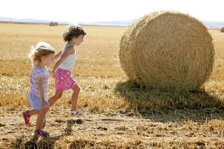 Girls playing with the round wheat dried bales outdoor summerの写真素材