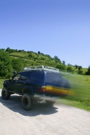 Blurred motion speedy 4x4 blue truck in the meadow road
