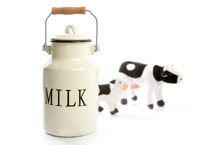 Milk urn white pot with blurred toy cows isolated on whiteの写真素材