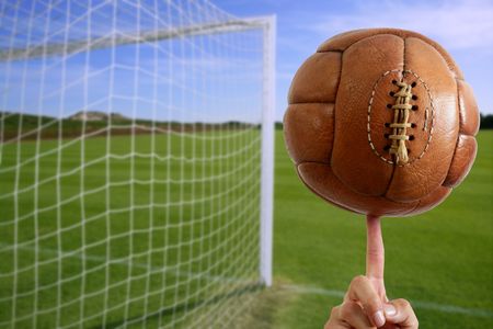Football vintage ball in hand net soccer goal green grass backgroundの写真素材