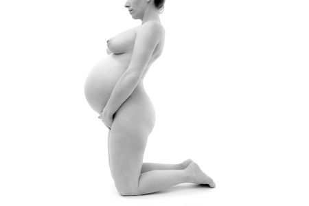pregnant woman on knees nude profile studio white backgroundの写真素材