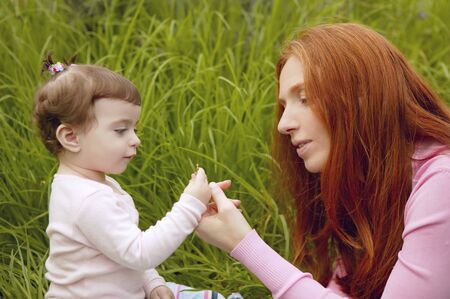 baby and redhead mother outdoor grass playing park togetherの写真素材