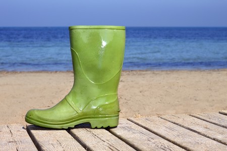 green boot on summer wooden beach soil unlucky fisherman metaphorの写真素材