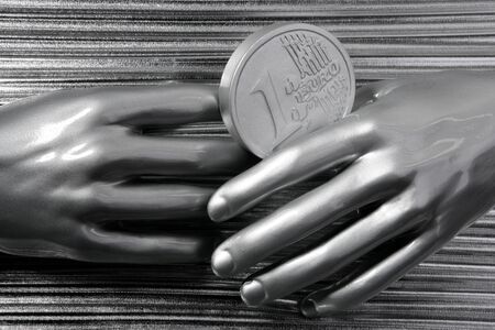 silver euro coins in futuristic robot gray metallic hands bank metaphorの写真素材