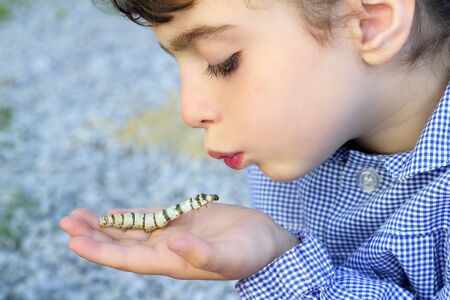 little girl palying with silkworm in hands with school uniform  の写真素材