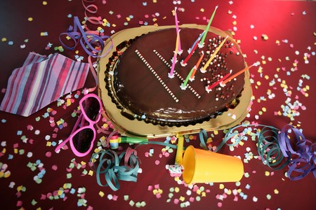 Chocolate holiday party cake on a messy confetti red tableの写真素材