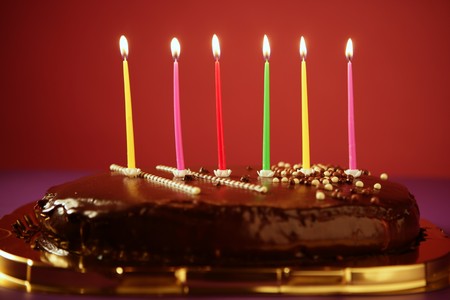 Colorful birthday light candles in a chocolate cake red background