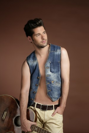 Handsome sexy young man musician guitar player portrait on brown