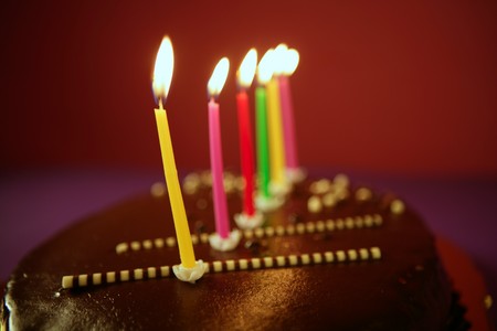 Colorful birthday light candles in a chocolate cake red background