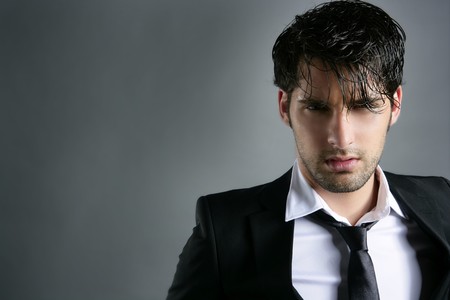 Fashion trendy suit young handsome man messy hairstyle dark portrait on grayの写真素材
