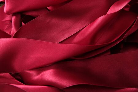 Red satin ribbons in a messy mess texture backgroundの写真素材