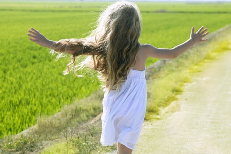 rear view running open arms little happy girl green meadow field trackの写真素材