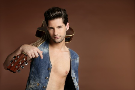 Handsome sexy young man musician guitar player portrait on brownの写真素材