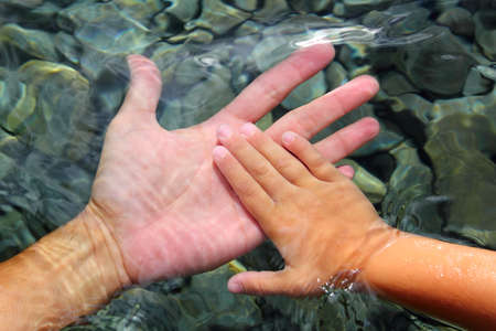 adult and children hands holding underwater wavy distortedの写真素材